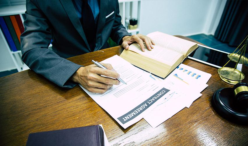 A person signing a new commercial enterprise contract agreement on a desk.