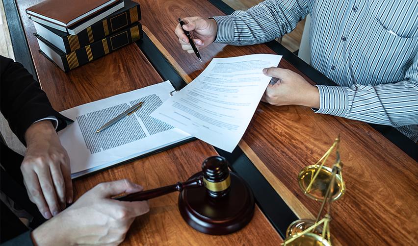 A person at an attorney's office, with documents and a gavel on the desk, discussing job creation requirements for conditional permanent resident status.