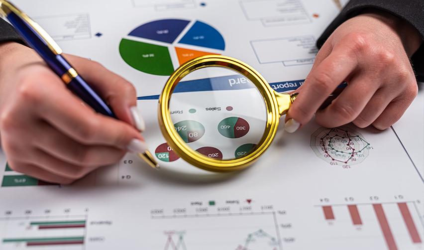 An Eb5 financial advisor examining investment opportunities on the investor's behalf using business graphs, charts, and a magnifying glass.