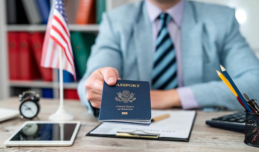 An USCIS official handing a U.S. passport to an immigrant investor green card holder.