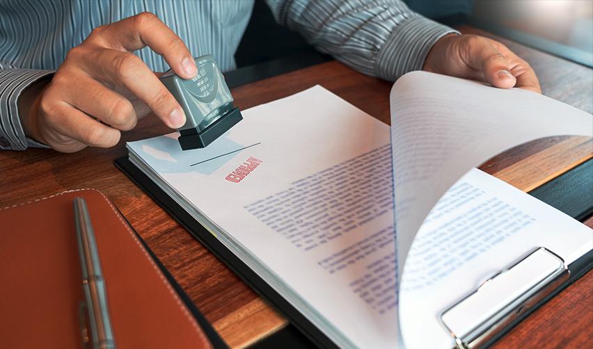 An adjudicator stamping some lawful permanent residence documents approved.