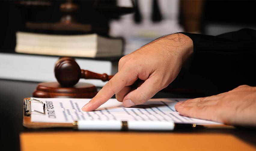 A judge's hand pointing at legal documents, implying EB-5 visa or immigration law reform.