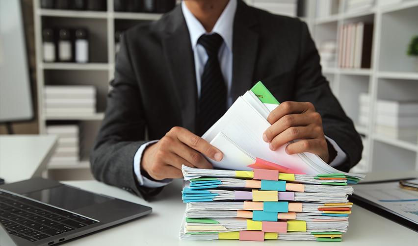 An immigration lawyer going through a stack of new commercial enterprise documents as part of the EB-5 regional center program.