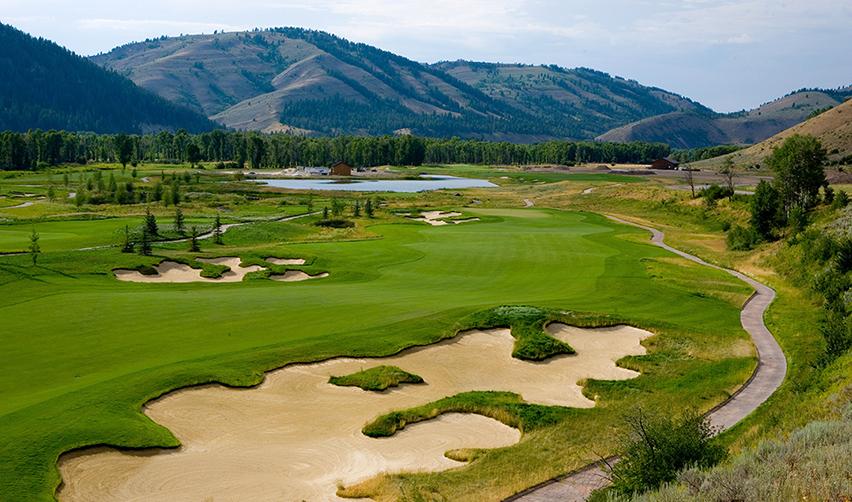 A golf course with sand bunkers and mountains in the background, part of the Snake River Sporting Club rural project grounds.
