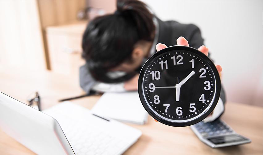 A distressed person with her head on her desk, holding a clock up to the camera, symbolizing immigrant investors frustrated with processing times. 