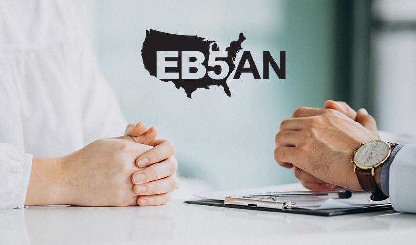 Close-up of hands on a table with documents about investment projects, under the EB5AN logo.