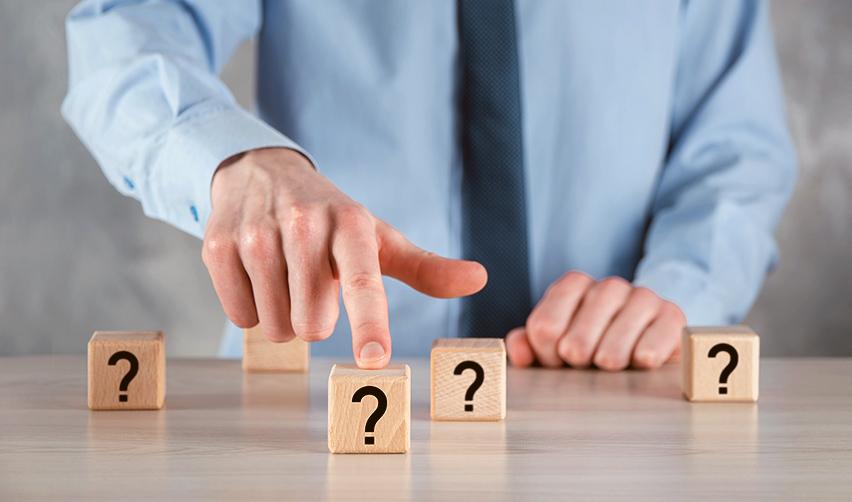 A hand pointing at wooden blocks with questions on them, symbolizing FAQs regarding lawful permanent resident status, eligibility criteria, required documentation, how to remove conditions on permanent resident card, etc.