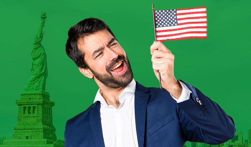 An EB5 alien investor holder smiling and holding up an American flag.