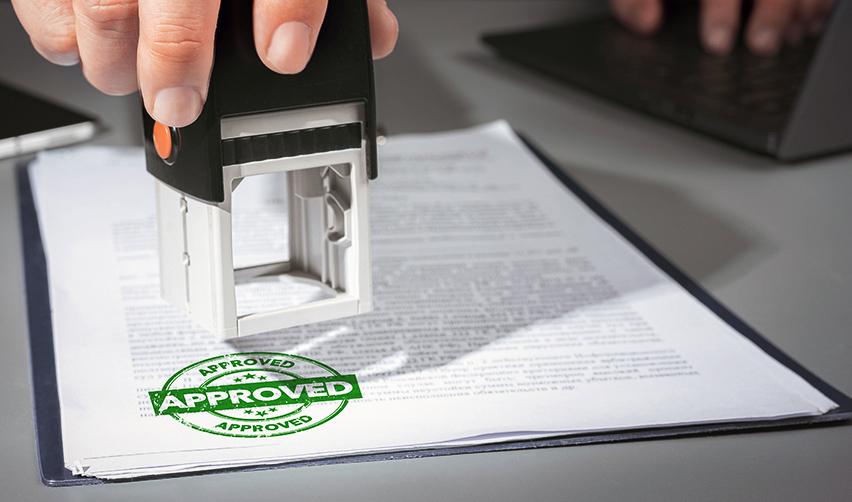 A hand stamping an immigrant petition with a green