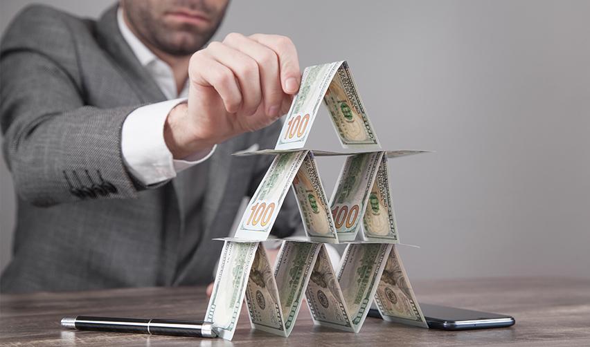 An EB5 investor building a structure using dollar bills, while trying to decide between EB5 debt or equity.