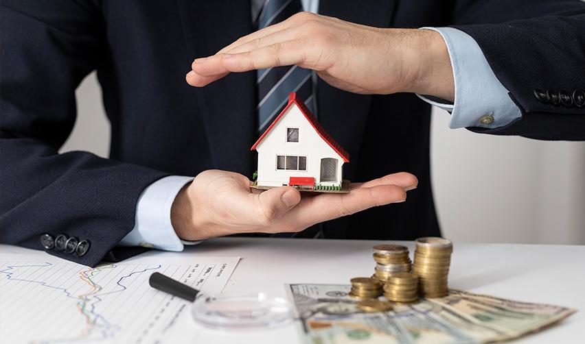 An investor holding a model house in his hands, with investment capital money on his desk, symbolizing EB5 capital stack.