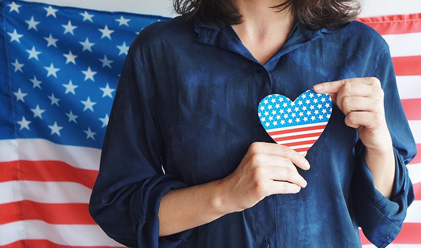An EB5 investor holding a heart-shaped cutout in the colors of the American flag.