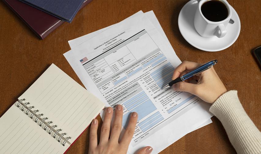 A person filling out Form I-485, application to register permanent residence or adjust status.