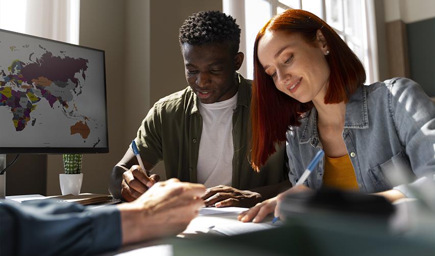 Two international students filling out different visa application forms after their F1 application is rejected.