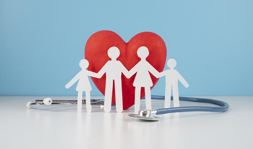 A paper cutout of a family in front of a big red heart and a stethoscope, symbolizing family access to healthcare as EB5 green card holders.