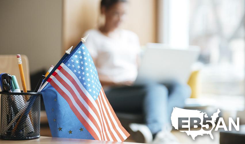 An EB5 green card holder student studying on a computer in the background, with the American flag in the foreground next to the EB5AN logo.