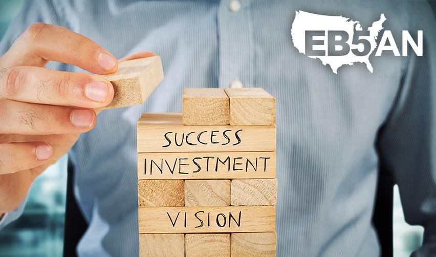 A regional center principal building a structure with wooden blocks with the words success, investment and vision on them, and the EB5AN logo on the corner.