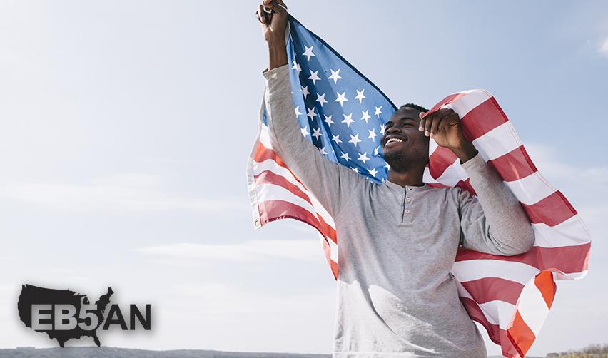 A foreign investor smiling and holding up a U.S. flag next to the EB5AN logo.