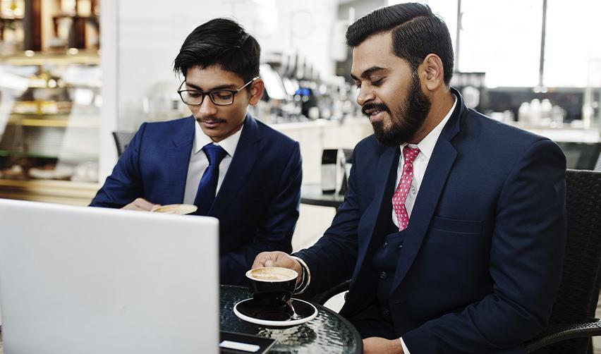 An EB5 investor family working together on a computer while drinking coffee.