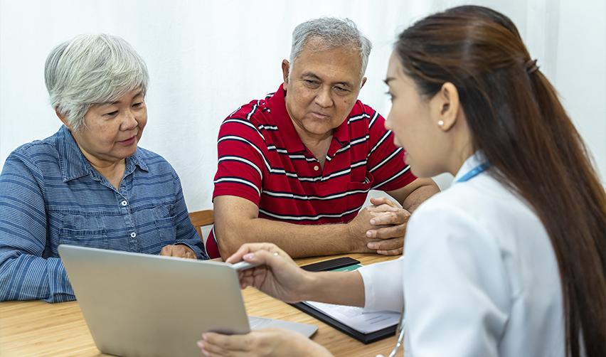 An elderly Asian couple looking at test results at a doctor's office.