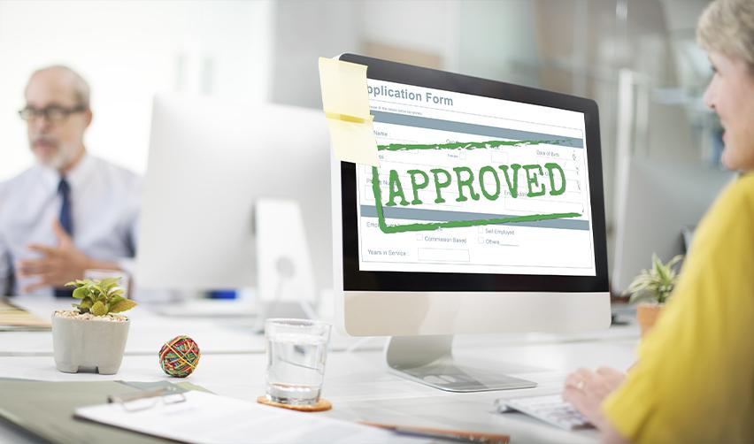 An EB5 investor looking at an approved sign of her visa application on a computer. She is obtaining a green card by creating jobs with the EB5 lower capital investment amount.