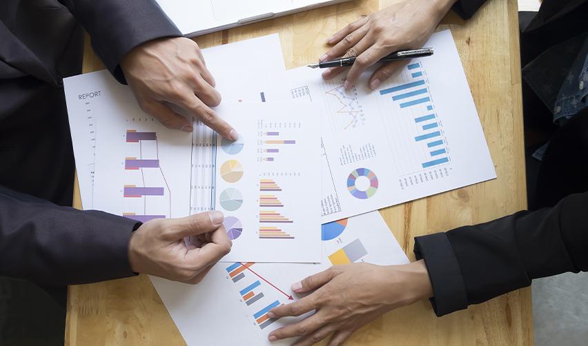 Two people discussing charts with project reports, symbolizing detailed project vetting by regional centers to ensure successful EB5 investments.
