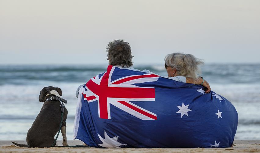 A family from Australia sitting by the beach with a flag around them.
