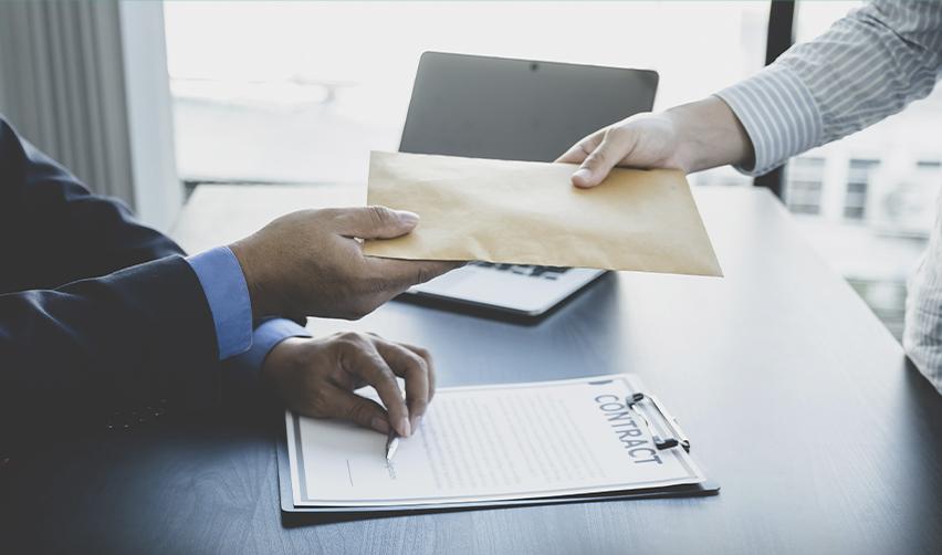 A close-up of two individuals exchanging a brown envelope over a contract on a desk, representing the process of filing for an EAD or EB5 Green Card and signing necessary documents for U.S. work authorization.