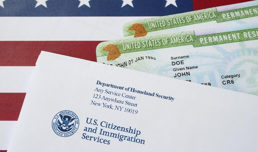 USCIS immigration envelope and green cards symbolizing successful EB5 visa approval and U.S. permanent residency.