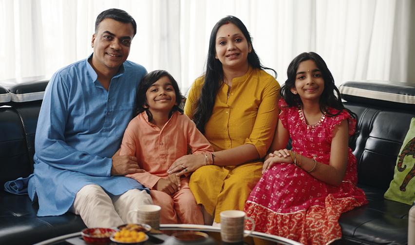 An Indian family sitting together, symbolizing how the EB5 program provides Green Card benefits to H1B visa holders and their dependents, ensuring long-term stability in the U.S.