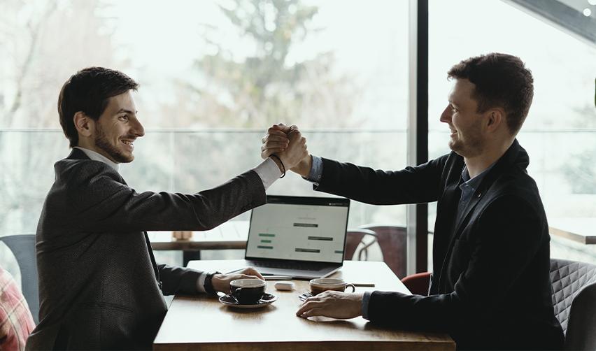 Two business professionals shaking hands after a successful agreement, highlighting the importance of investment and employment-based visa options in the journey toward securing a Green Card for Israelis.
