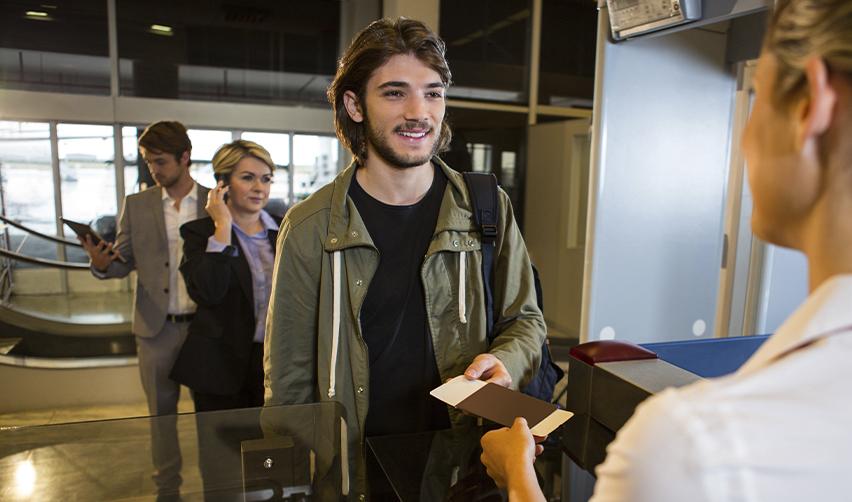Young man presenting travel documents at an airport checkpoint, symbolizing EB5 investors using advance parole for international reentry during I-485 processing.