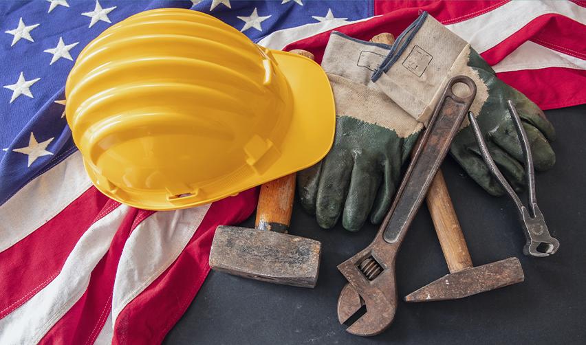 Hard hat, gloves, and construction tools placed on a U.S. flag, symbolizing EB5 job creation and the American labor market supported by immigrant investment.