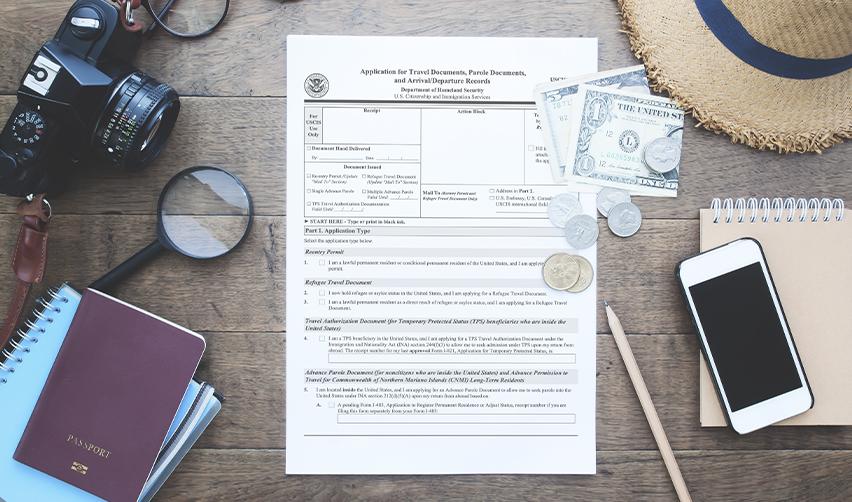 Application for Travel Document (Form I-131) alongside a passport, phone, and camera, representing advance parole and reentry permit applications for EB5 immigrants.