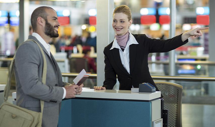 Business traveler receiving directions from an airline staff member, conveying legal international travel and reentry for Green Card holders with a reentry permit.