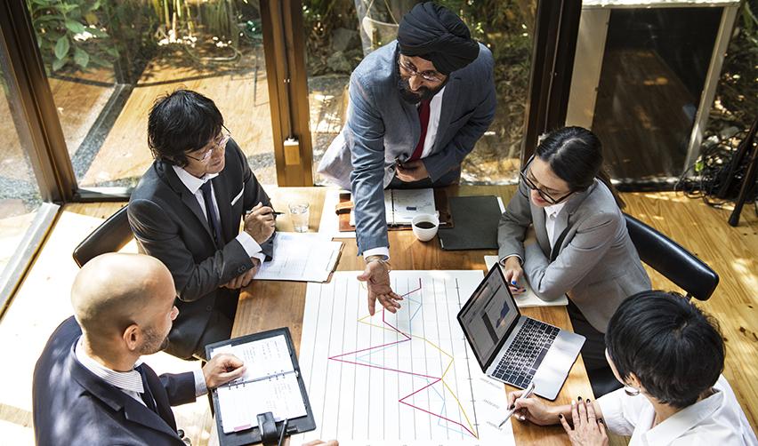 Diverse group of professionals reviewing charts in a bright office, representing EB5 investment planning, strategy, and the role of EB5 firms like EB5AN in successful immigration outcomes.