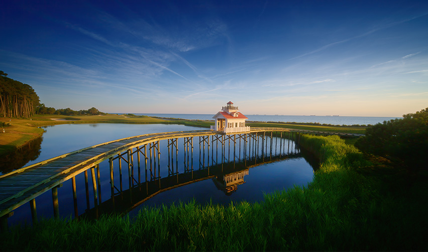 A bridge over water with a house and grass