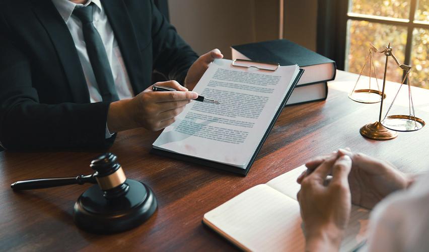 An EB5 immigration attorney reviewing legal documents with a client across a desk, symbolizing support with source of funds documentation and project review.