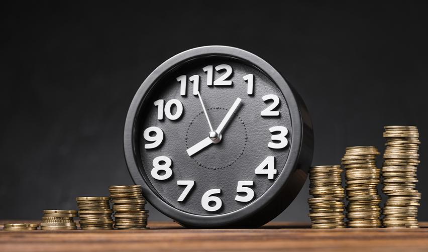 A black clock surrounded by stacks of coins, illustrating the concept of time-bound EB5 investments and financial risk management.