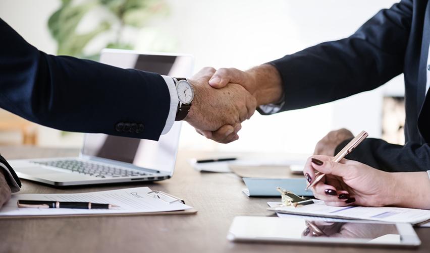Two business professionals shaking hands over signed documents, representing investor confidence and finalizing an EB5 investment agreement.