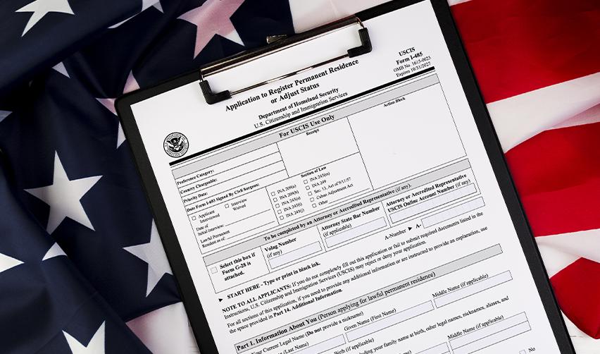 USCIS Form I-485 on a clipboard placed over an American flag, illustrating the adjustment of status process for EB5 investors applying for U.S. residency.