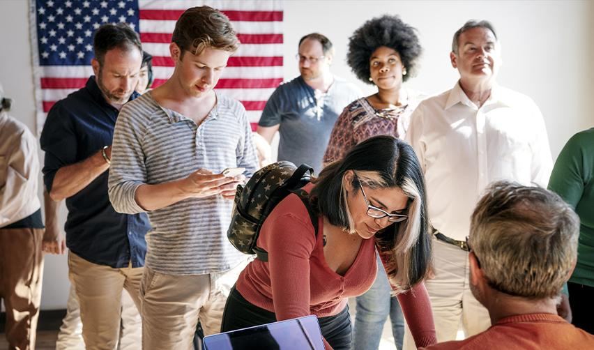 A diverse group of people standing together in front of a U.S. flag, symbolizing the EB5 visas allocated to people from various countries through set-aside visas.