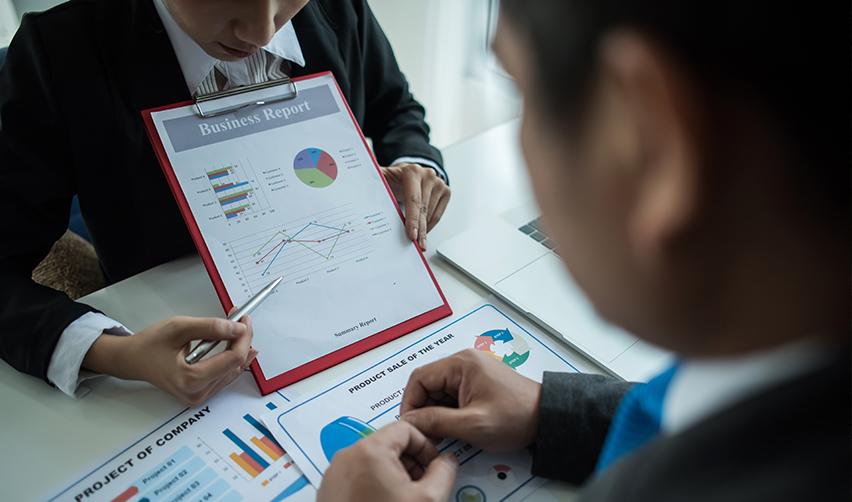 Two professionals reviewing a business report with charts and graphs, symbolizing transparency and project tracking in EB5 investments.
