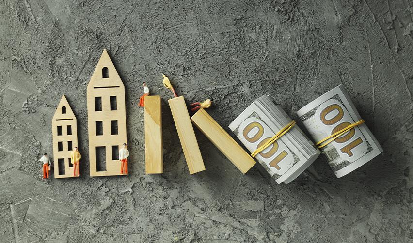 Wooden miniature houses and figurines arranged like dominoes falling toward bundles of U.S. dollars, symbolizing EB5 real estate investment risks and financial outcomes.