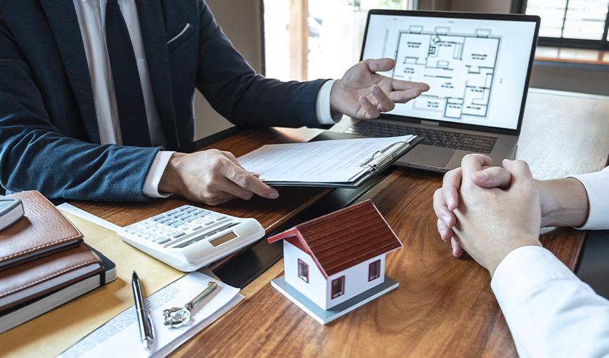 Business meeting with documents, calculator, and laptop showing building plans, highlighting financial due diligence and real estate evaluation in EB5 investments.