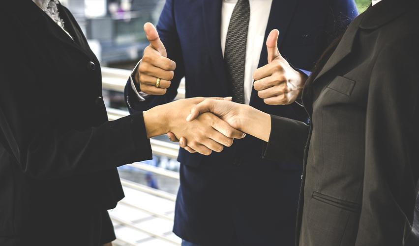 Close-up of businesspeople shaking hands with thumbs up, representing trusted partnerships and successful outcomes for EB5 investors working with leading regional centers like EB5AN.