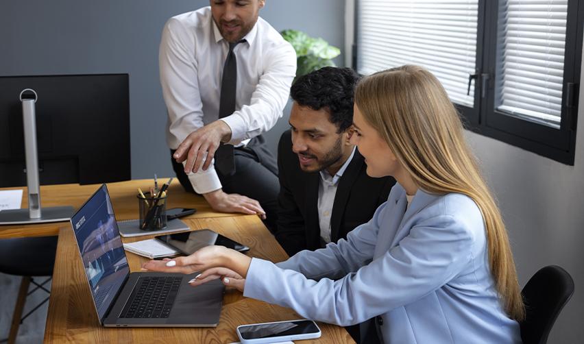 Team of professionals collaborating at a laptop in an office, highlighting the role of attorneys, accountants, and advisors in preparing EB5 source of funds petitions.