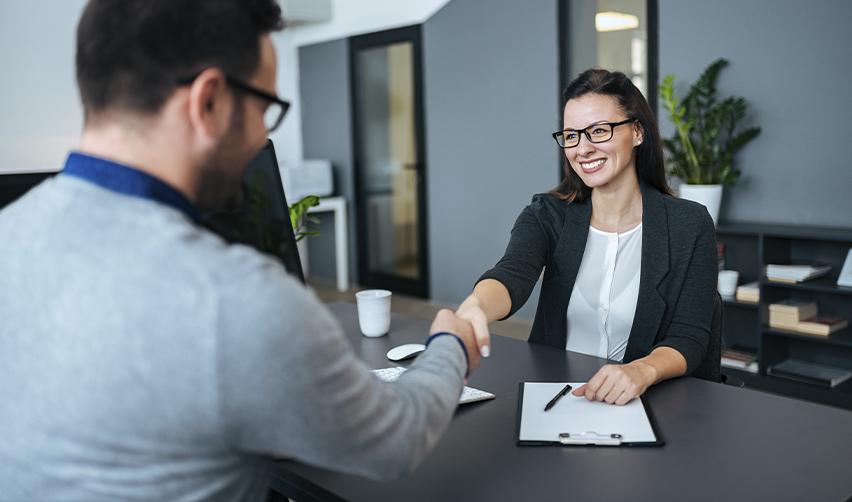 Smiling businesswoman shaking hands with a colleague, representing successful EB5 project approval and investor confidence.