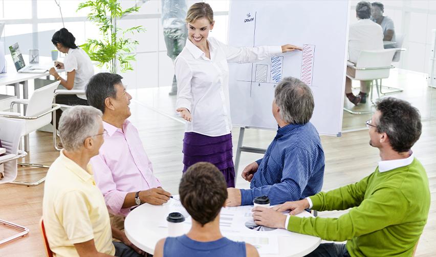 A professional presenting bar graphs to colleagues in a conference room, reflecting transparency, compliance, and regular reporting in EB5 developer oversight.
