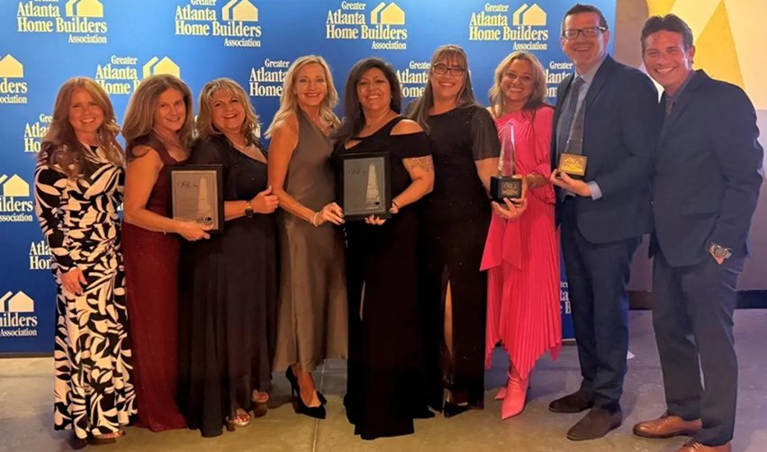 A group of Kolter Homes team members standing together at the Atlanta Home Builders Association’s OBIE Awards ceremony, holding gold and silver awards recognizing Cresswind communities for excellence in home design, marketing, and community development.